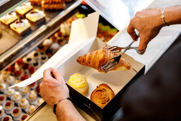 Pasticcere che prepara un vassoio di dolci per asporto